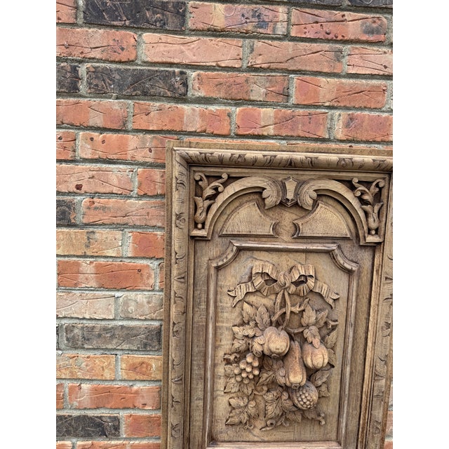 Hand-carved solid wood wall panel depicting a whimsical fruit motif in deep relief, framed by an architectural border. The...