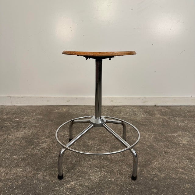 Mid Century Modern Workshop Stool. This stool features a round wooden seat that swivels and adjusts in height. The base is...