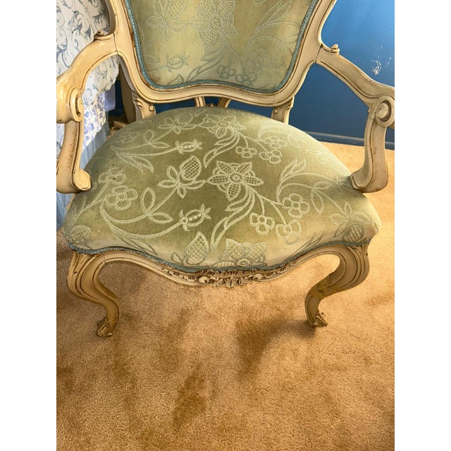 Elegant vintage Louis XV–style armchair featuring a beautifully carved solid wood frame in a distressed cream finish. The...