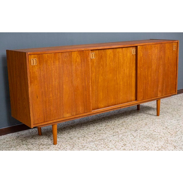Large teak sideboard with three sliding doors, Denmark, 1960. It offers ample storage space in the two left compartments,...