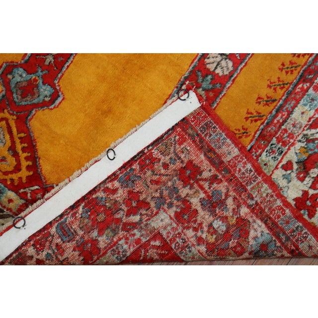 An early 20th century angora wool Oushak rug with a bright saffron color field with a double scroll column prayer motif....