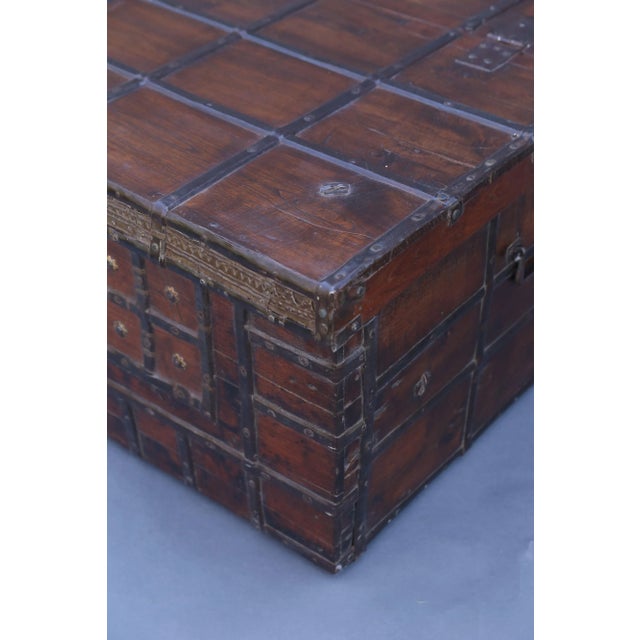 A 19th-Century British Colonial Anglo-Indian solid teak and iron bound trunk. It is the perfect coffee table size and...