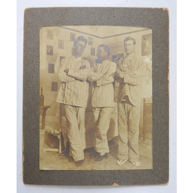 Antique sepia toned circa 1910 photograph of 3 men dressed in pajamas in a bedroom with walls covered with pinups. Single...