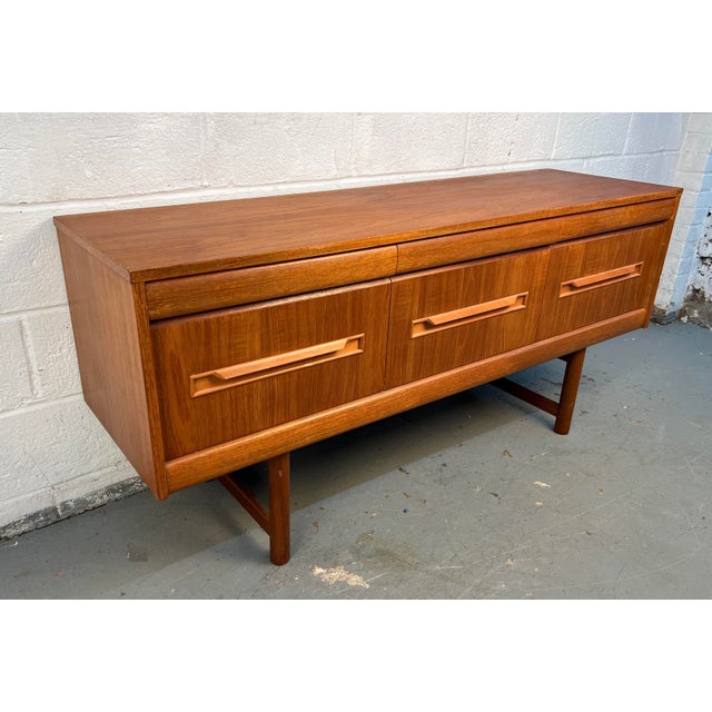 Elegant mid-century modern teak server manufactured by Elliotts of Newbury. Features clean Danish-inspired lines, warm...