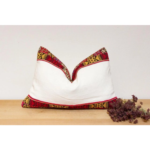 This handcrafted pillow features a vibrant, hand-stitched textile border created by the Lakai tribe of Uzbekistan. It is a...