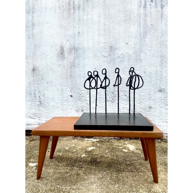 An exceptional original iron sculpture featuring an elegant composition of stylized abstract figures gathered in quiet...