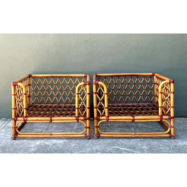 This vintage pair of lounge chairs is built from honey-toned rattan poles bent into low, boxy frames with softly rounded...