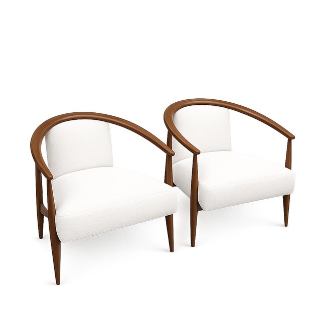 Modern mid century lounge chairs done in a cream leather upholstery. The chairs have a walnut finish. The chairs are circa...