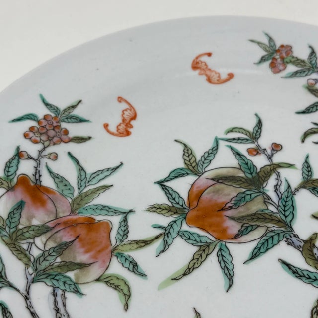 A vintage porcelain plate, hand-decorated with peach trees and fruit, and flying bats. Good condition.