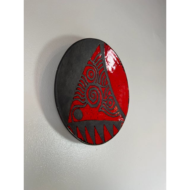 A beautiful Mid-century hand made and painted black- and red glazed artistic studio pottery decorative wall plate. Signed...
