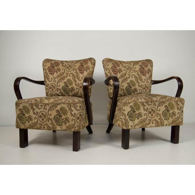 Elegant pair of upholstered club armchairs featuring sculptural bentwood armrests and decorative floral-pattern...