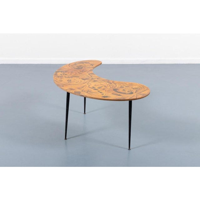 Unique 1950s side table/coffee table produced in Italy. It has black coated steel legs with unique curved veneered table...