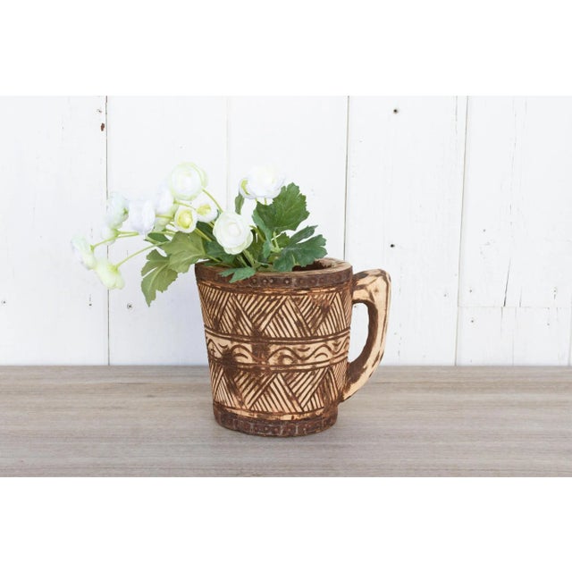 Rustic and primitive, this Himachal pot has hand-carved tribal design with a rounded handle and metal straps on the...