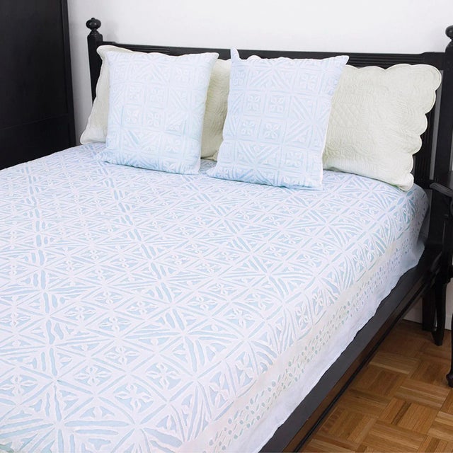 A sophisticated symmetrical pattern is cut-out in sheer white cotton organdy and hand-sewn on sky blue cotton fabric to...