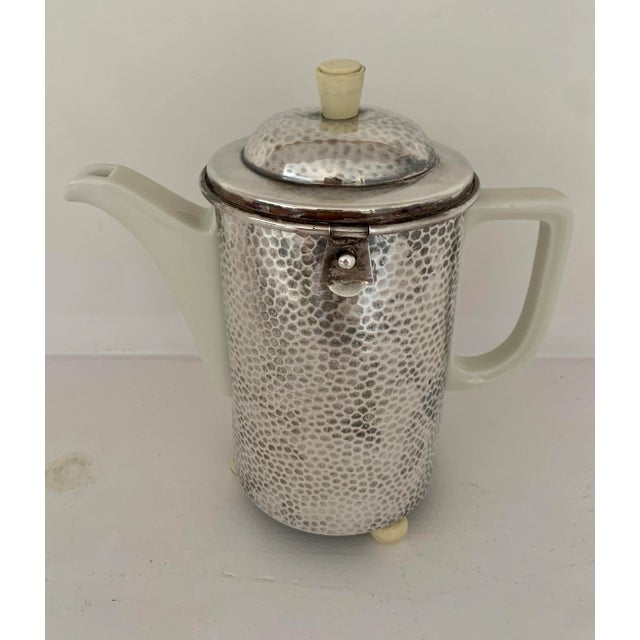 Art Deco, Bauscher Weiden porcelain coffee or tea pot fully insulated with felt in a hammered silver cozy by WMF. The...