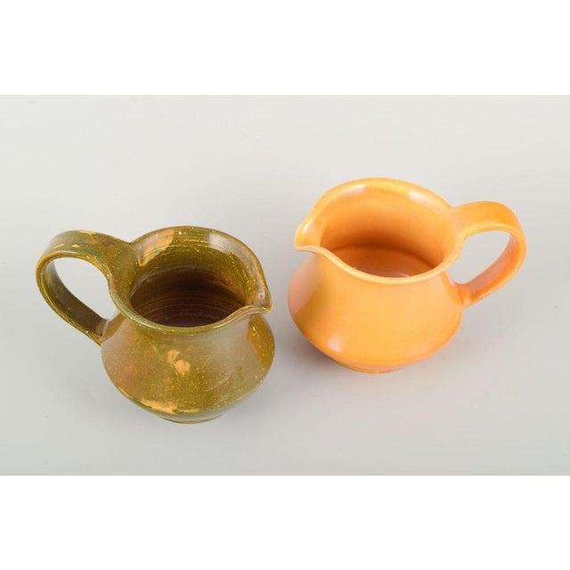 Kähler. Two ceramic pitchers with uranium glaze. Glazed in green and orange uranium glaze respectively. Classic form with...