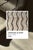 Crisp waves, drawn row after row. Fine charcoal chevron lines ripple horizontally across this piece in tight, even rows,...