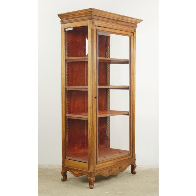 Vintage European vitrine cabinet made of carved wood with a beveled glass front and sides. It features three adjustable...