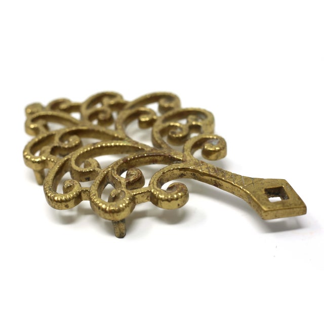 A vintage, solid brass trivet, with a vine-like form. Good condition.
