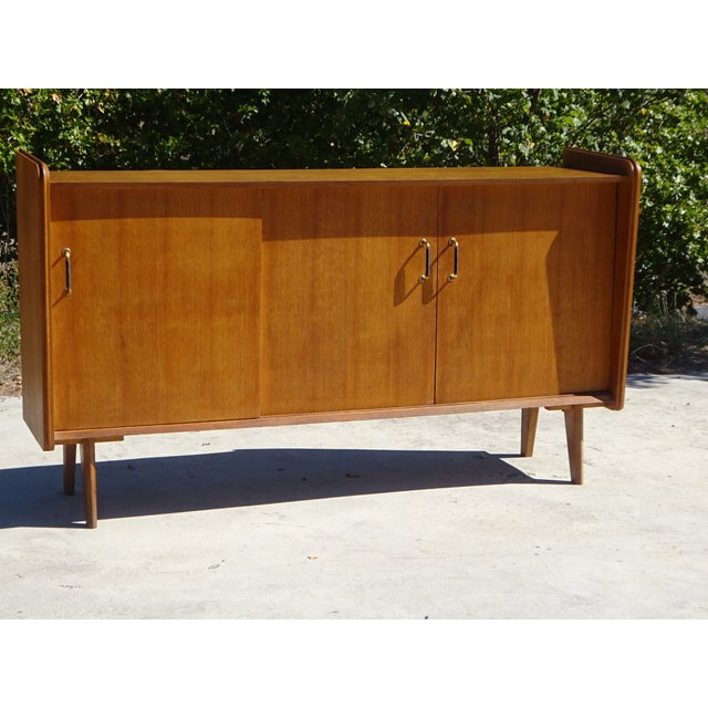 Three-door sliding sideboard produced by Société Auxiliaire du Meuble (S.A.M), established in Bordeaux in the 1950s. An...