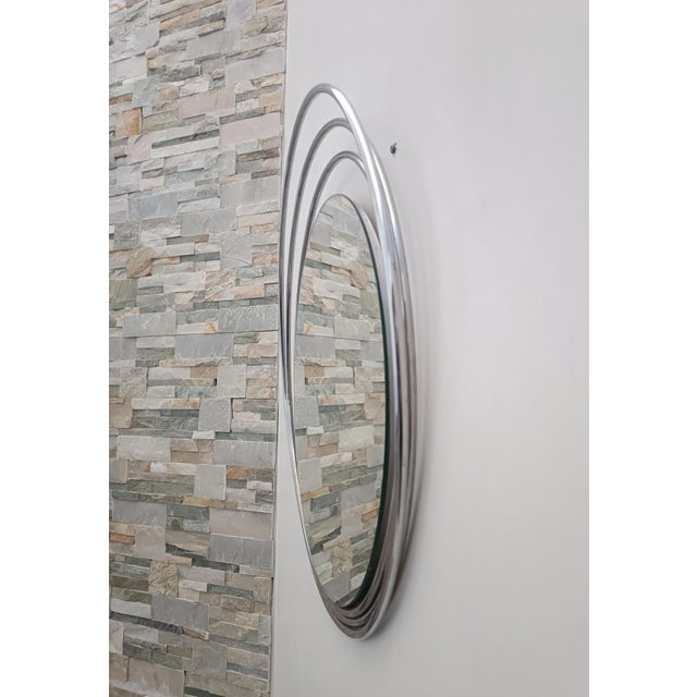 Magnificent space age design mirror. Italy, 1970s. Chrome-plated metal frame. The off-center glass is surrounded by three...