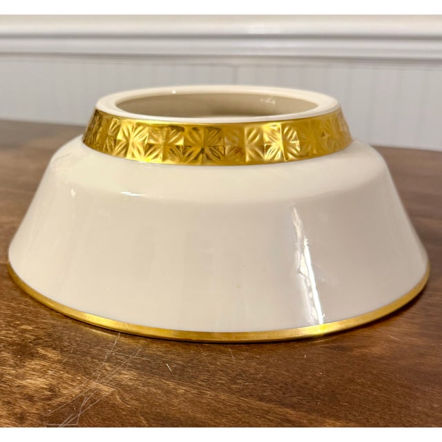 This is an elegant serving bowl from Lenox featuring a classic ivory base color adorned with a distinctive gold rim and a...