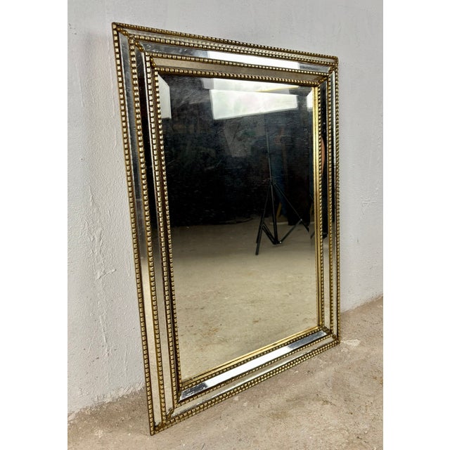 Elegant wall mirror featuring a sophisticated brass frame with decorative beaded detailing and beautifully beveled...