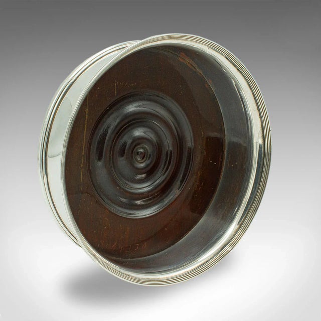 This is a vintage wine bottle coaster. An English, silver plate and walnut decorative drink stand, dating to the early...