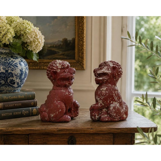 A wonderfully weathered pair of antique cast stone foo dogs, retaining their original red painted finish with beautifully...