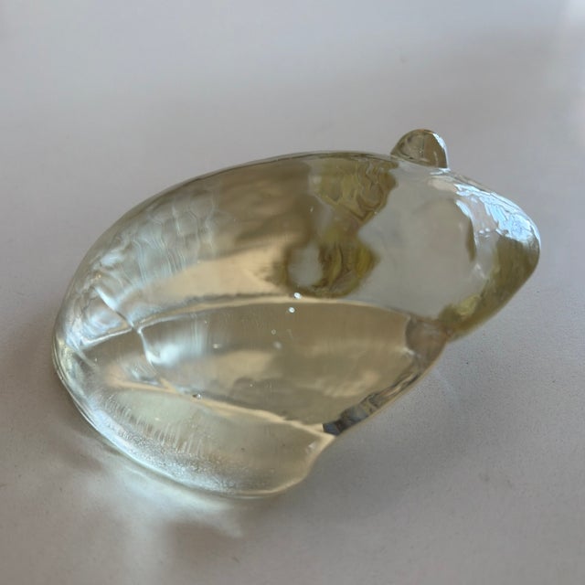 Hand-blown art glass frog sculpture with an organic ribbed form and clear glass featuring a warm champagne tint. The piece...