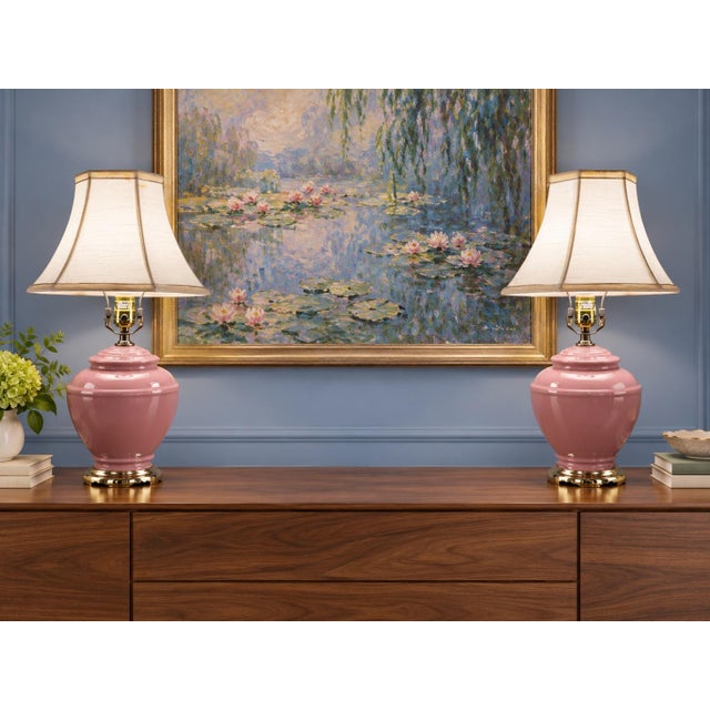 1980’s matching pair of rose-pink glass ginger jar table lamps with glossy bodies, stepped shoulders, brass-tone footed...