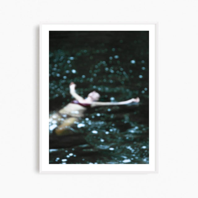 This fine art photography print presents an ethereal female figure taking a late swim in dark waters. With a contemporary...