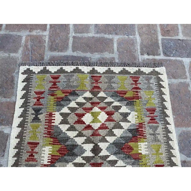 Bring a touch of bohemian flair to your home with this handwoven wool kilim, featuring a striking tribal design. The...