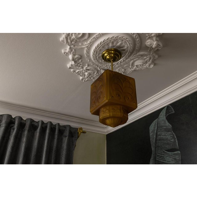 Elegant French Art Deco pendant from the 1930s. Molded amber glass shade with geometric relief and softly rounded...