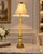 Table lamp with an ornate gold-tone base with urn and foliate motifs, and a tailored fabric shade trimmed with crystal-...