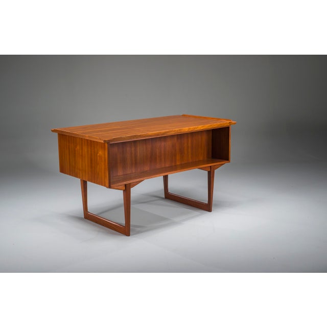 Elegant freestanding danish teak desk from the 1960s featuring distinctive raised lip edges and a fully finished back,...