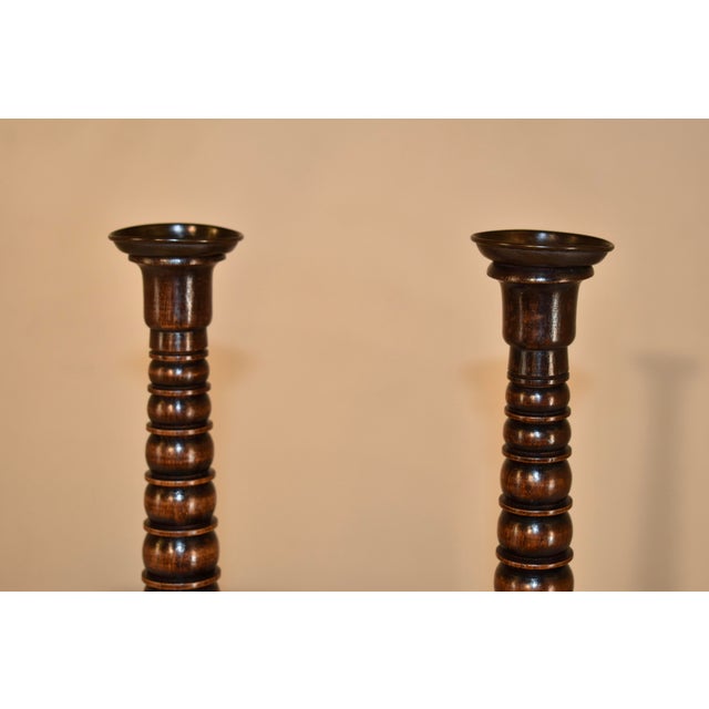 Pair of late 19th century turned oak candlesticks from England. The candle cups are made from hand turned brass, sitting...