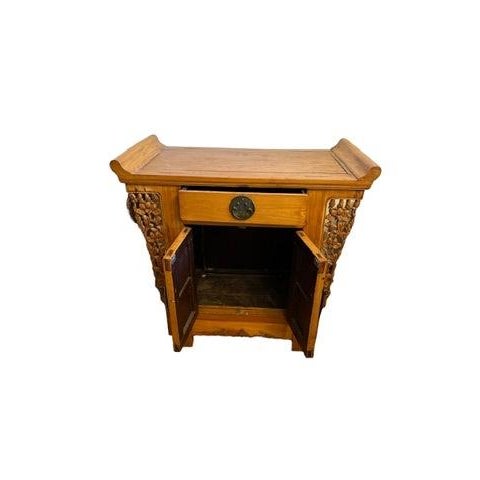 A beautifully crafted vintage Chinese elmwood cabinet featuring hand-carved floral panels and original brass hardware....