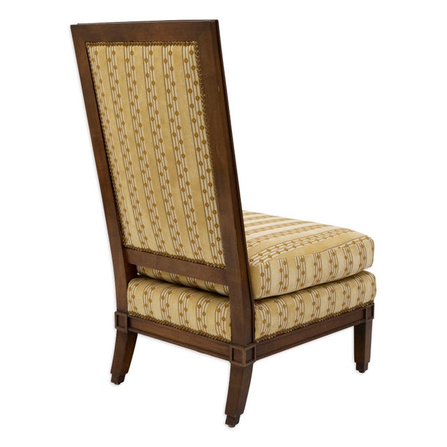 This Baker style accent chair features a tall, gently angled back and a sturdy wooden frame with clean, classic lines. The...