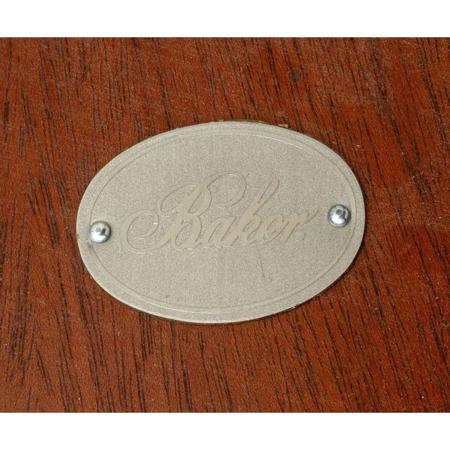 Elegant Baker Furniture center table featuring a round mahogany-toned top with a subtly raised edge, supported by four...