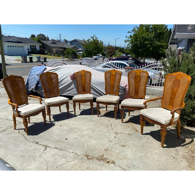 The American of Martinsville Campaign Light Wood & Cane Dining Chairs are a set of vintage dining chairs made in the...