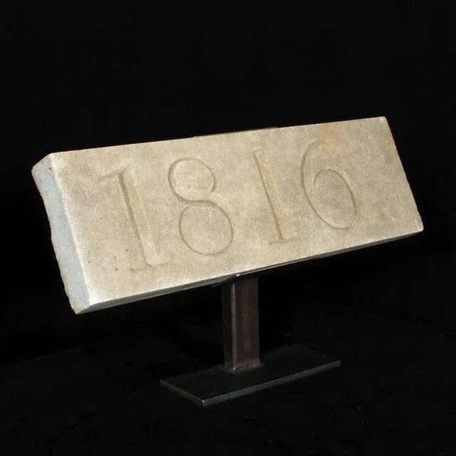 A carved stone architectural block custom mounted on a metal stand, elevating the early 19th century stone into a 21st...