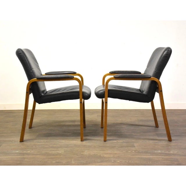 A pair of mid century modern teak bent wood lounge chairs with blue leather upholstry made by Ekornes Stressless. Seat...