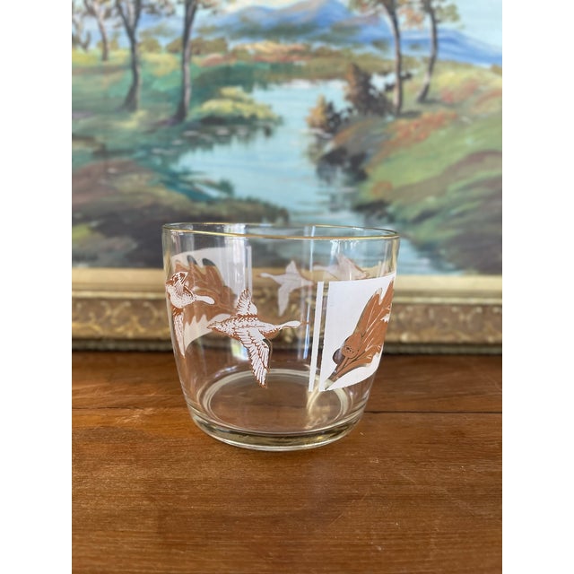 This vintage mid-century glass ice bucket features a richly detailed outdoor sporting motif, showcasing alternating panels...