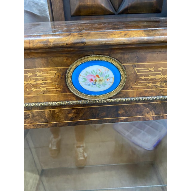 Pair of antique inlaid display cabinets with ceramic medallions on hidden casters.