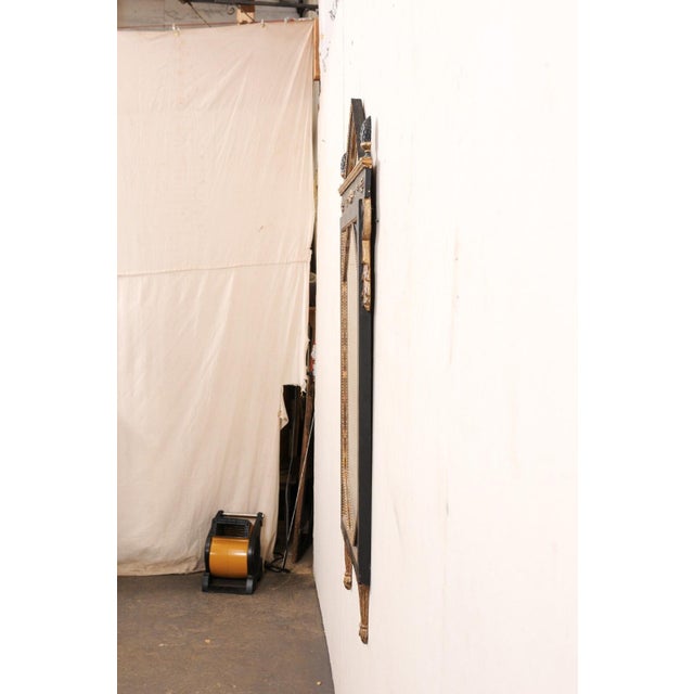 An Italian neoclassical style carved and painted wood mirror from the early 20th century. This antique mirror from Italy...