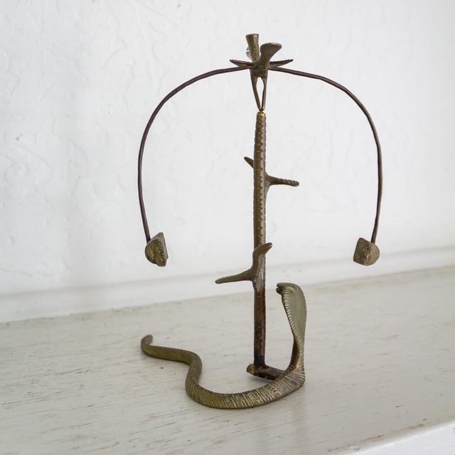 This three-dimensional brass kinetic sculpture depicts a cobra snake at the base of a cactus, interacting with small birds...