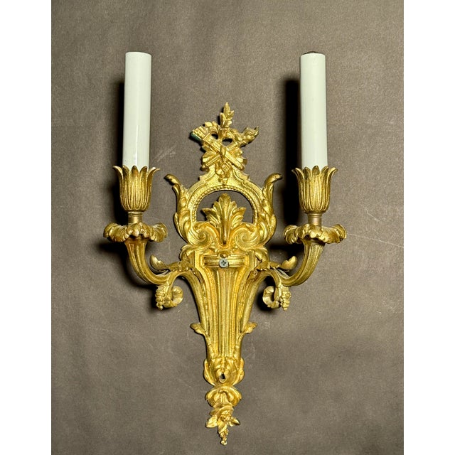 A refined pair of early 20th century French gilt bronze wall sconces in the Louis XVI style, distinguished by their...