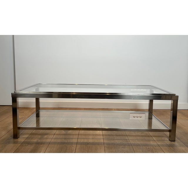 This large 2 tiers coffee table is made of chrome with 2 glass shelves. The top glass is inserted in a chrome frame. This...