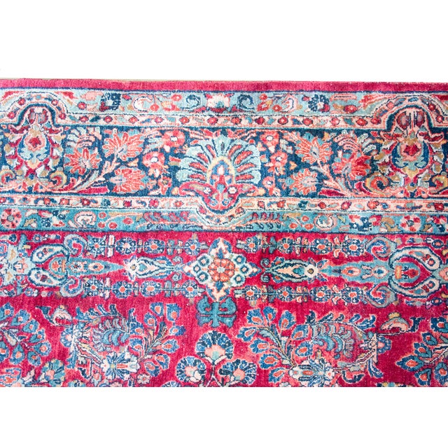 An antique Persian Sarouk rug from the 1930s, featuring a dense all-over floral design on a vibrant red field. The...